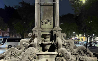 Stone fountain with dragon sculptures in Hanoi Old Quarter at night.