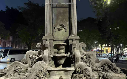 Stone fountain with dragon sculptures in Hanoi Old Quarter at night.