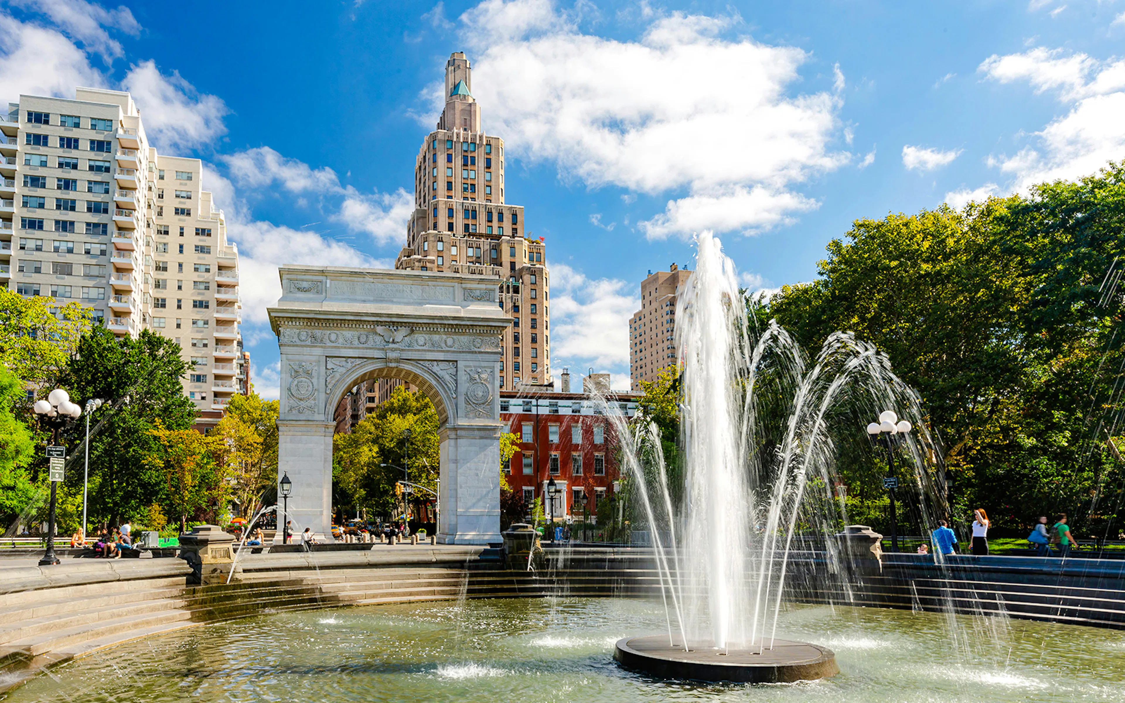 Triumphal Arch and fountain in Washington Square Park, New York City, under a sunny sky.
