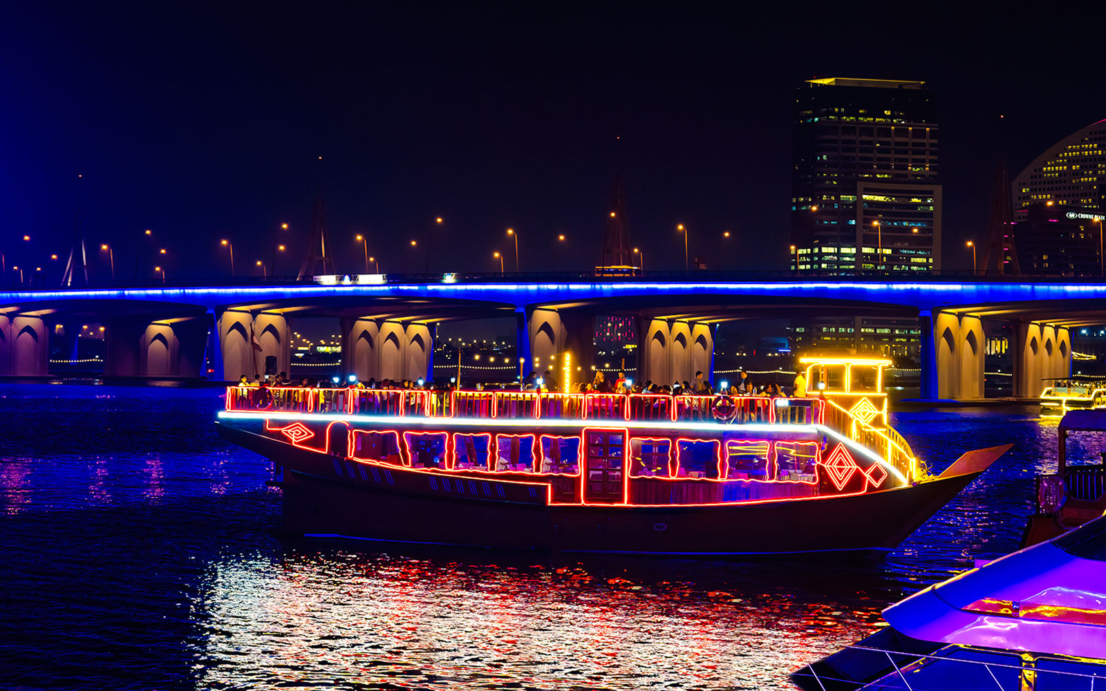 Dhow cruise with colorful lights on Dubai Creek at night.