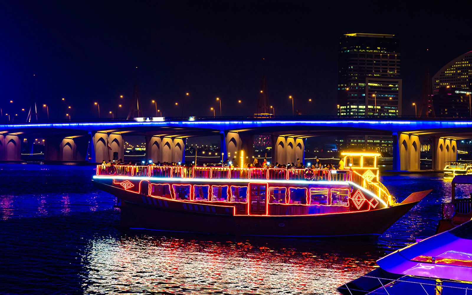 Dhow cruise with colorful lights on Dubai Creek at night.