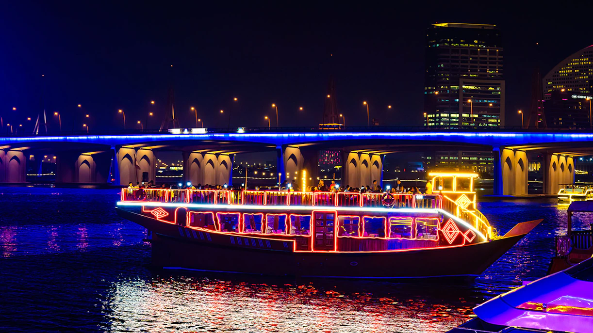 Dhow cruise with colorful lights on Dubai Creek at night.