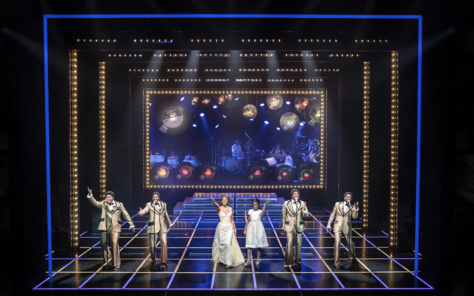 Performers on stage during "The Drifters Girl" musical with band in background.