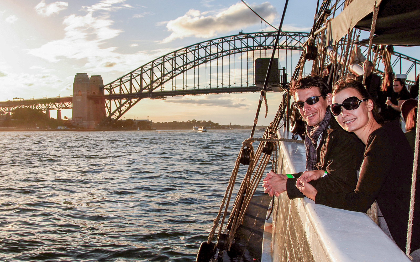 Couple on a tall ship enjoying Sydney Harbour views with Sydney Harbour Bridge in the background.