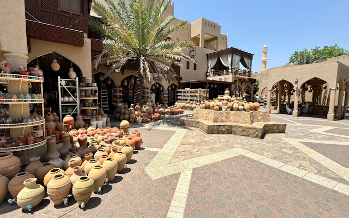 Pottery display at Nizwa Souq, Oman, with traditional clay pots and palm tree.