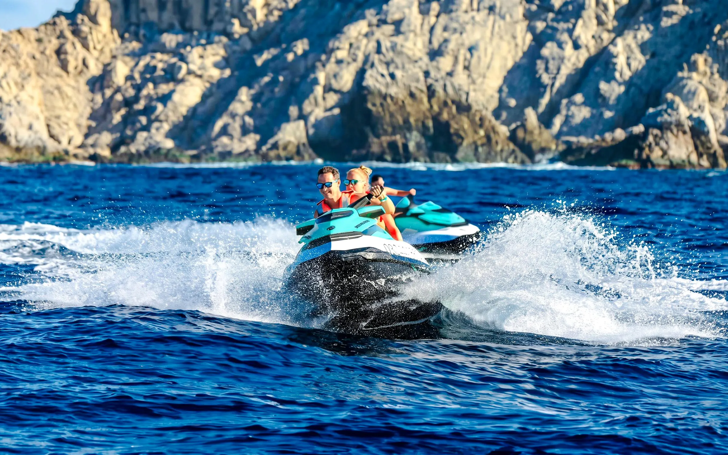 Jet skiing on the blue waters of Cannes, French Riviera, with rocky cliffs in the background.
