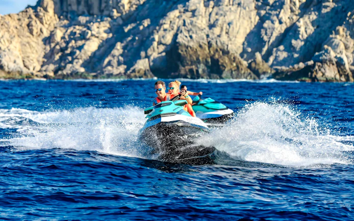 Jet skiing on the blue waters of Cannes, French Riviera, with rocky cliffs in the background.