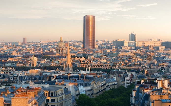 Montparnasse Tower rising above Paris skyline at sunset.