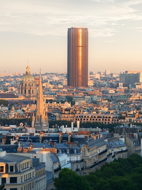 Montparnasse Tower rising above Paris skyline at sunset.