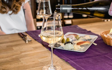 Wine being poured into a glass at a hidden wine bar with a cheese platter nearby.