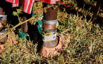 Maasai ankle jewelry and sandals on grass, Zanzibar village experience.