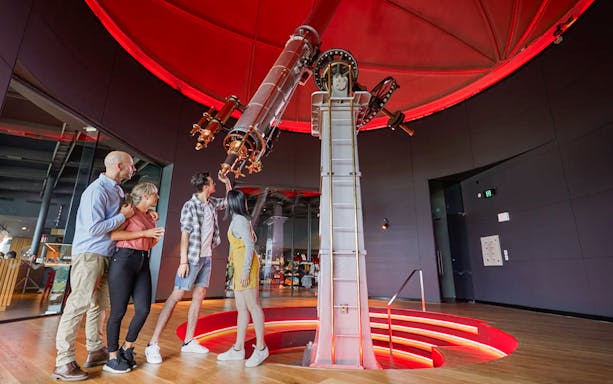 Guests examining telescope at Dark Sky Indoor Cultural Astronomy Experience.