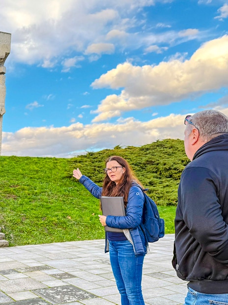 Tour guide explaining the Płaszów Concentration Camp memorial to visitors.