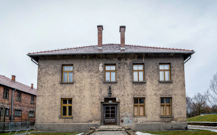 Auschwitz-Birkenau Museum building with brick chimneys and barred windows.