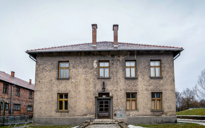 Auschwitz-Birkenau Museum building with brick chimneys and barred windows.