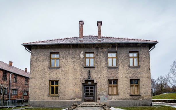 Auschwitz-Birkenau Museum building with brick chimneys and barred windows.