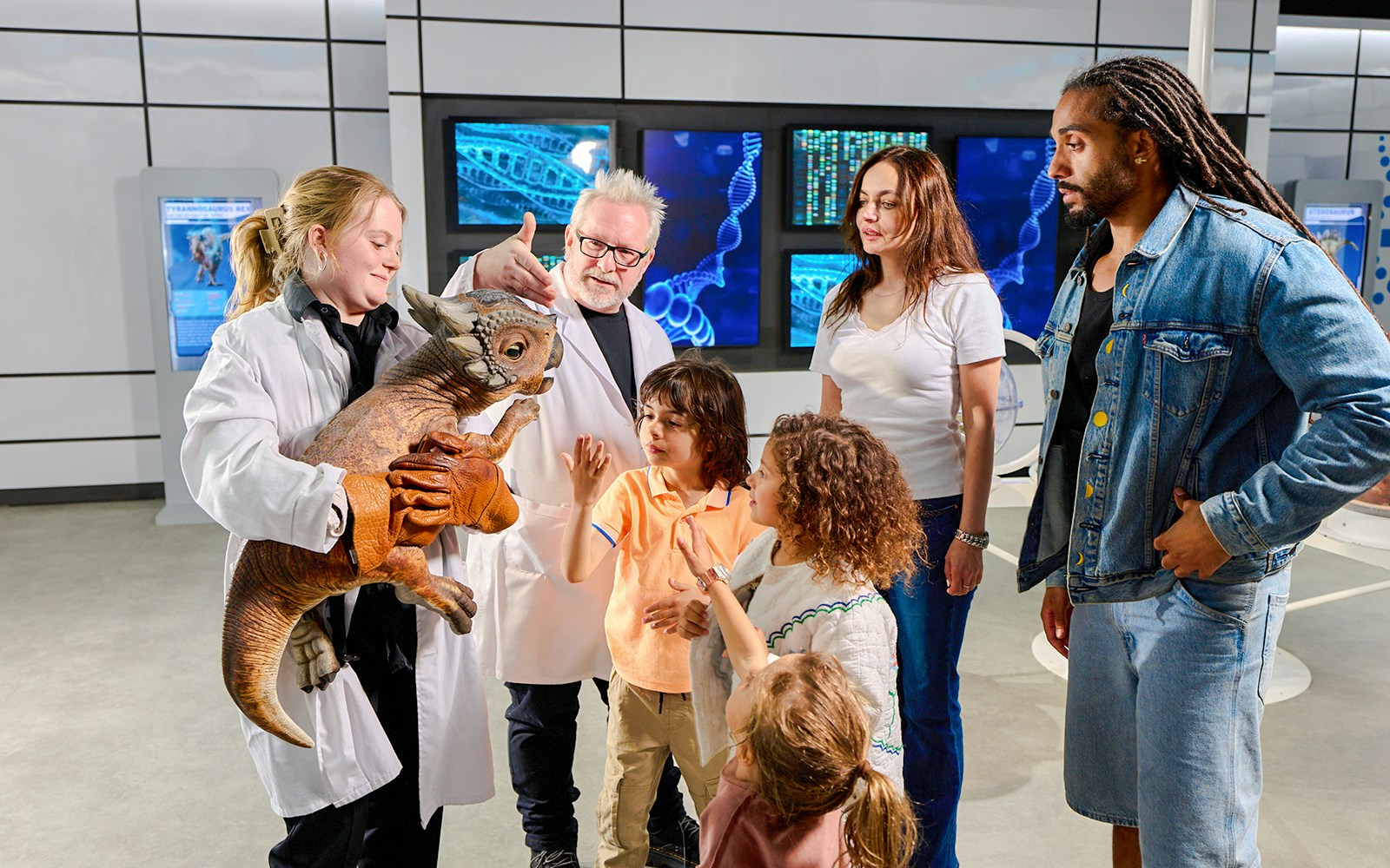 trainer and tourists interacting with little dinosaur