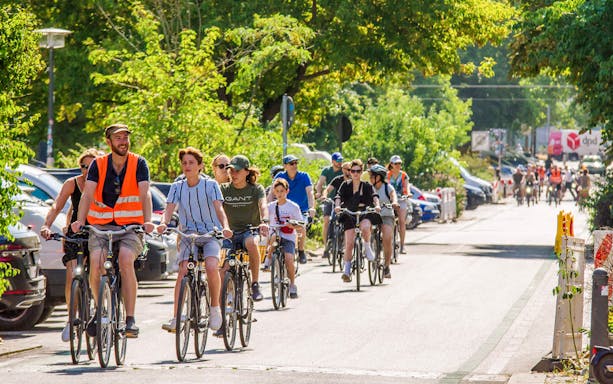 Group biking through a leafy street on a guided tour in Berlin.