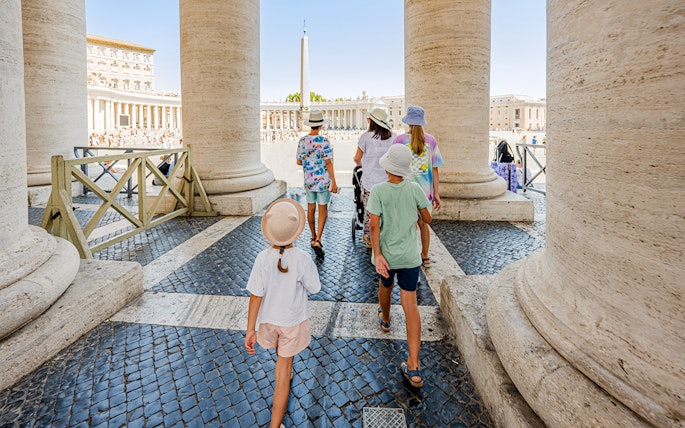Visitors walking through columns on a VIP tour of the Vatican Museums, Rome.