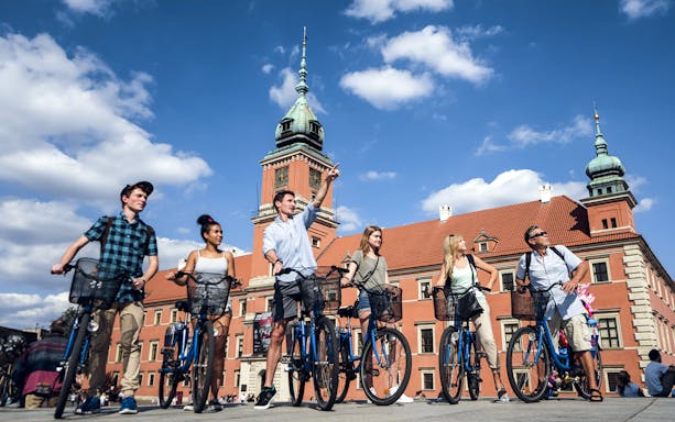 Group biking in front of Royal Castle, Warsaw on a sunny day.