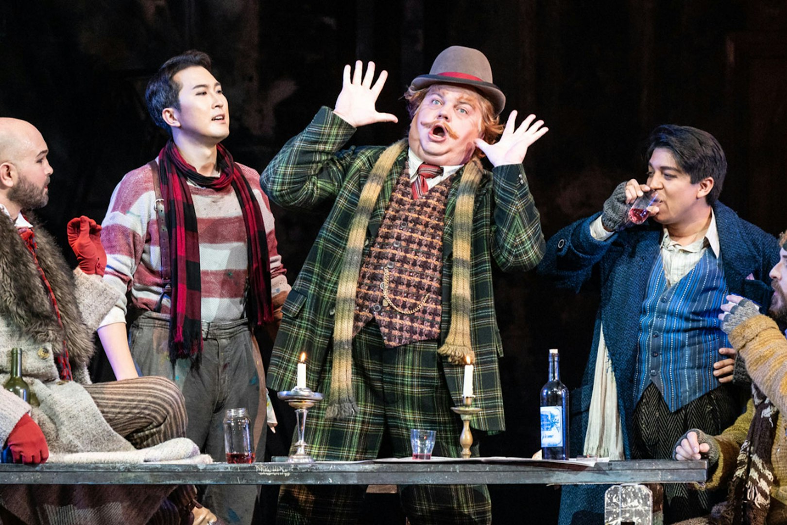 Opera performers in a lively scene from La Bohème, with expressive gestures and period costumes.