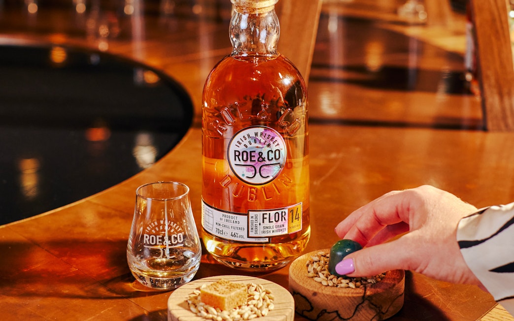 Roe & Co whiskey bottle and glass on a table at the distillery in Dublin.