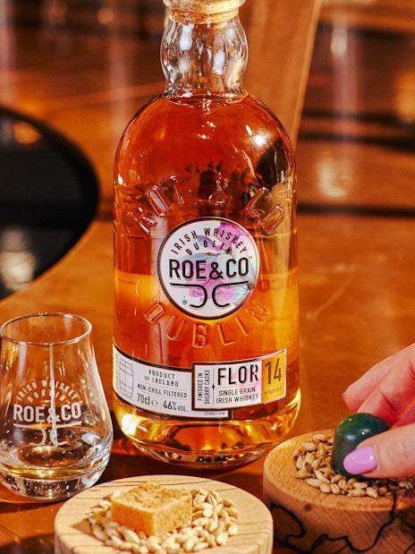 Roe & Co whiskey bottle and glass on a table at the distillery in Dublin.