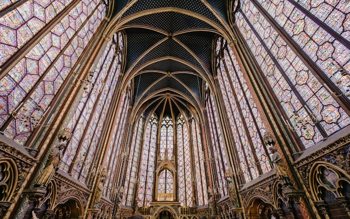 Sainte-Chapelle interior with ornate stained glass windows and vaulted ceiling in Paris.