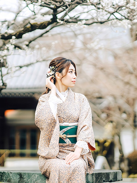 Japanese woman in kimono sitting under plum blossoms in Kyoto.