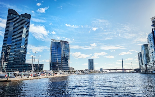 Melbourne skyline and docked boats on the Yarra River during Williamstown ferry cruise.