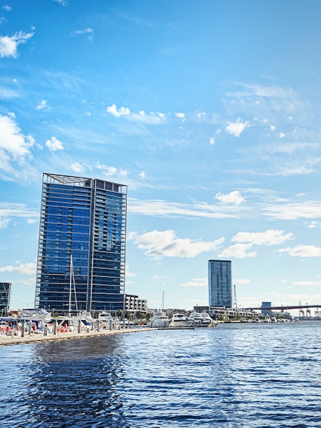 Melbourne skyline and docked boats on the Yarra River during Williamstown ferry cruise.