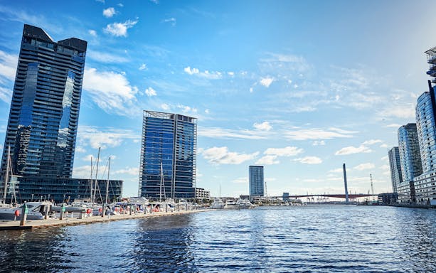 Melbourne skyline and docked boats on the Yarra River during Williamstown ferry cruise.