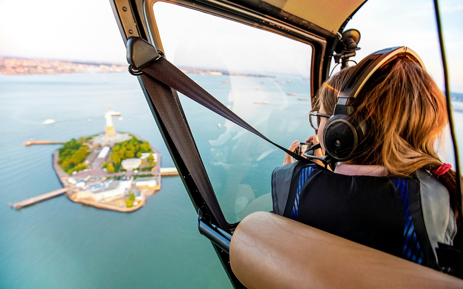 Helicopter view of Liberty Island, New York, with passenger taking photos.