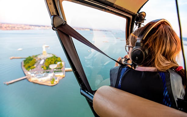 Helicopter view of Liberty Island, New York, with passenger taking photos.