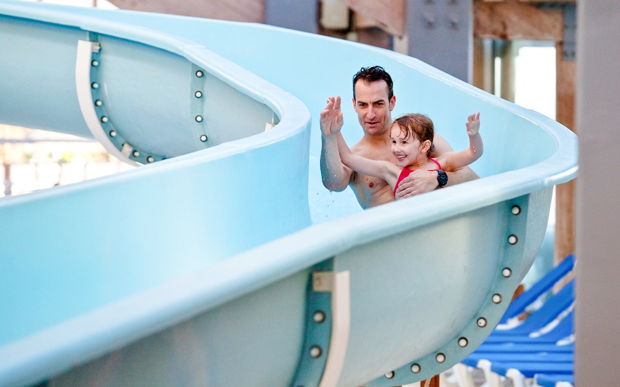 Father and daughter enjoying a waterslide at Aquaboulevard de Paris.