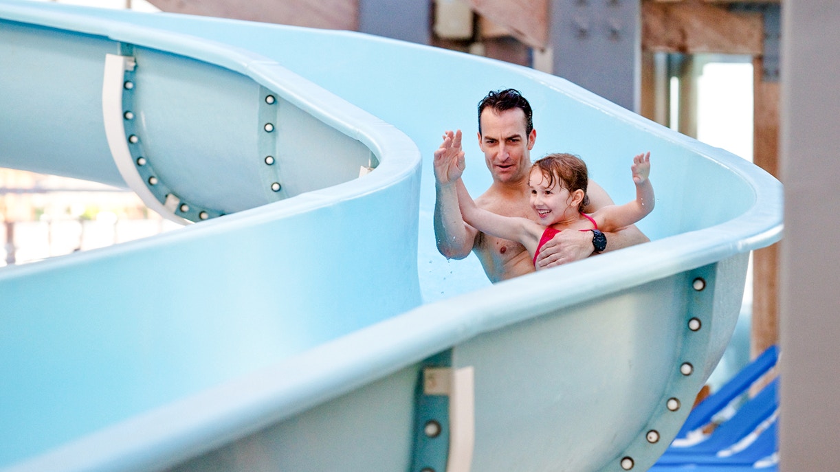 Father and daughter enjoying a waterslide at Aquaboulevard de Paris.