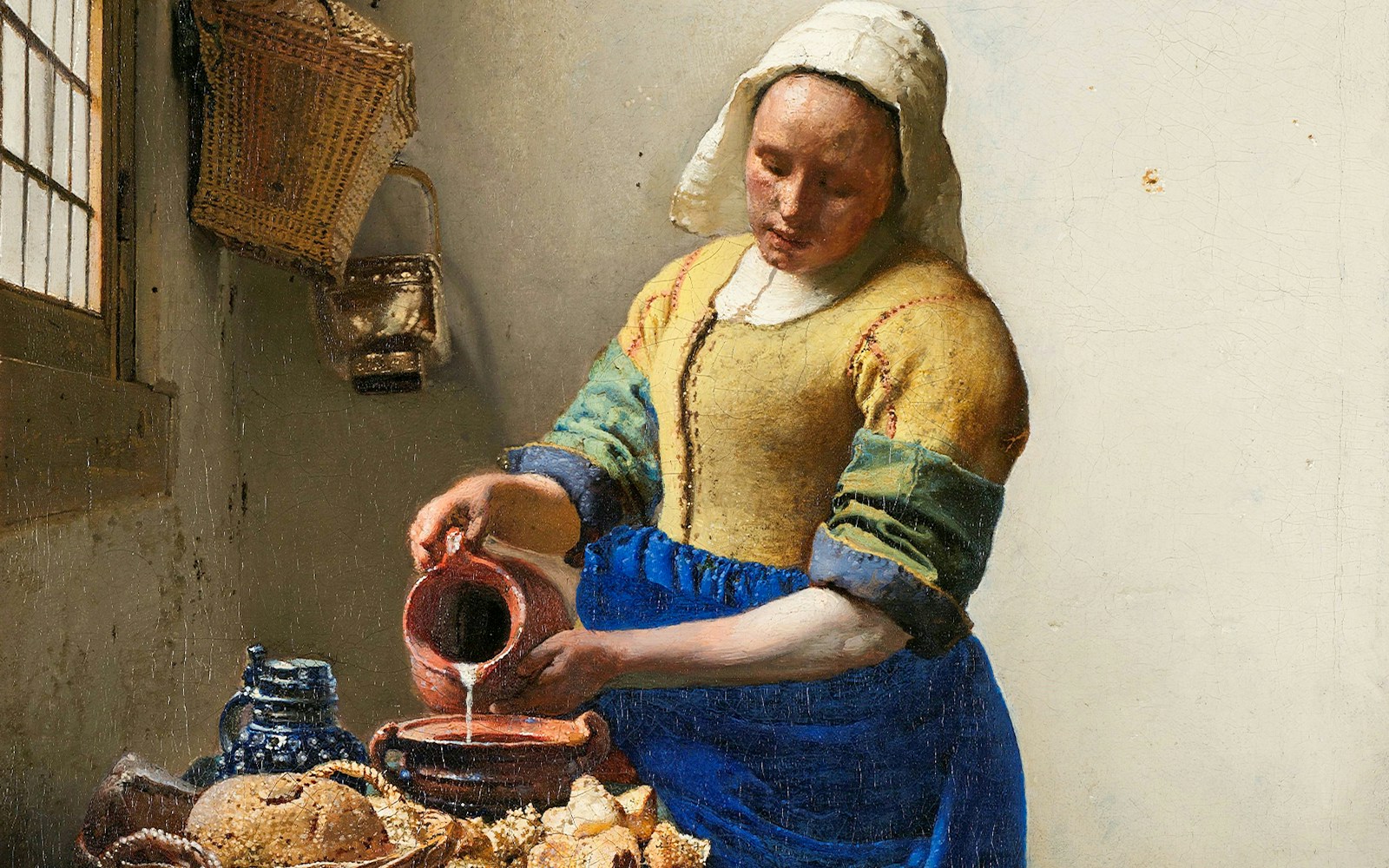 Woman pouring milk in Vermeer's "The Milkmaid," c. 1660, with bread and pottery on the table.