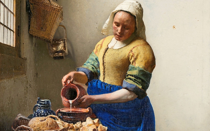 Woman pouring milk in Vermeer's "The Milkmaid," c. 1660, with bread and pottery on the table.