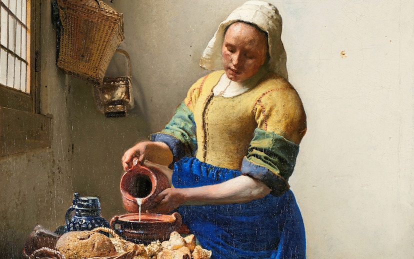 Woman pouring milk in Vermeer's "The Milkmaid," c. 1660, with bread and pottery on the table.