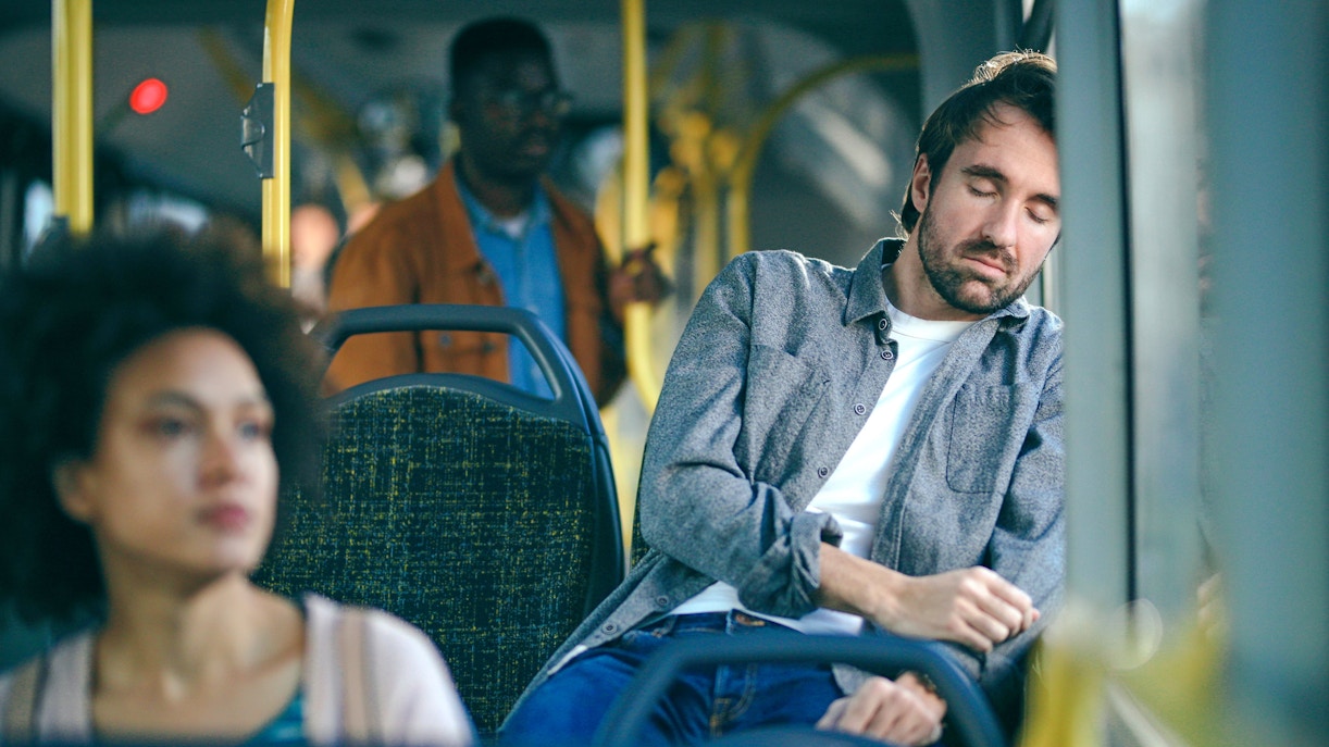 Tourist sleeping on a bus, appearing tired and exhausted.