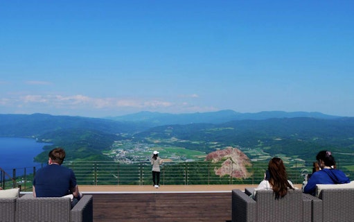 Viewing platform overlooking Mt. Usu and Lake Toya, Japan, with visitors enjoying the scenery.