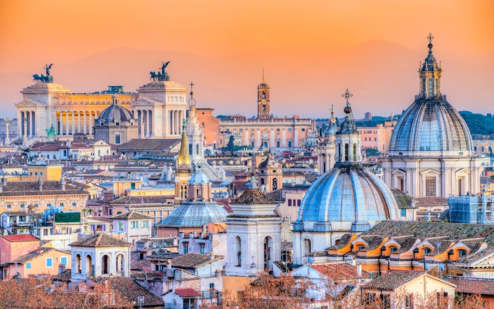 Rome skyline with St. Peter's Basilica and Altare della Patria at sunset.