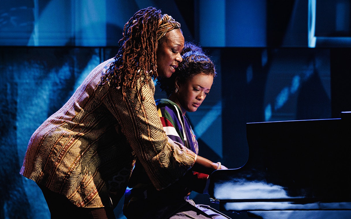 Two people playing a piano on stage in Hell's Kitchen.
