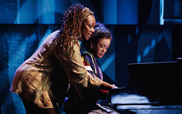Two people playing a piano on stage in Hell's Kitchen.
