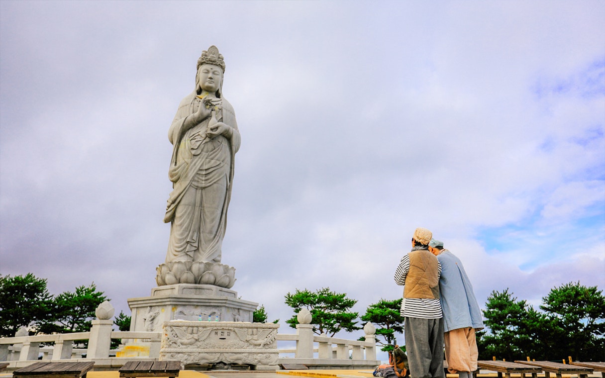 Statue at Naksansa Temple with visitors, Mt. Seorak, South Korea.