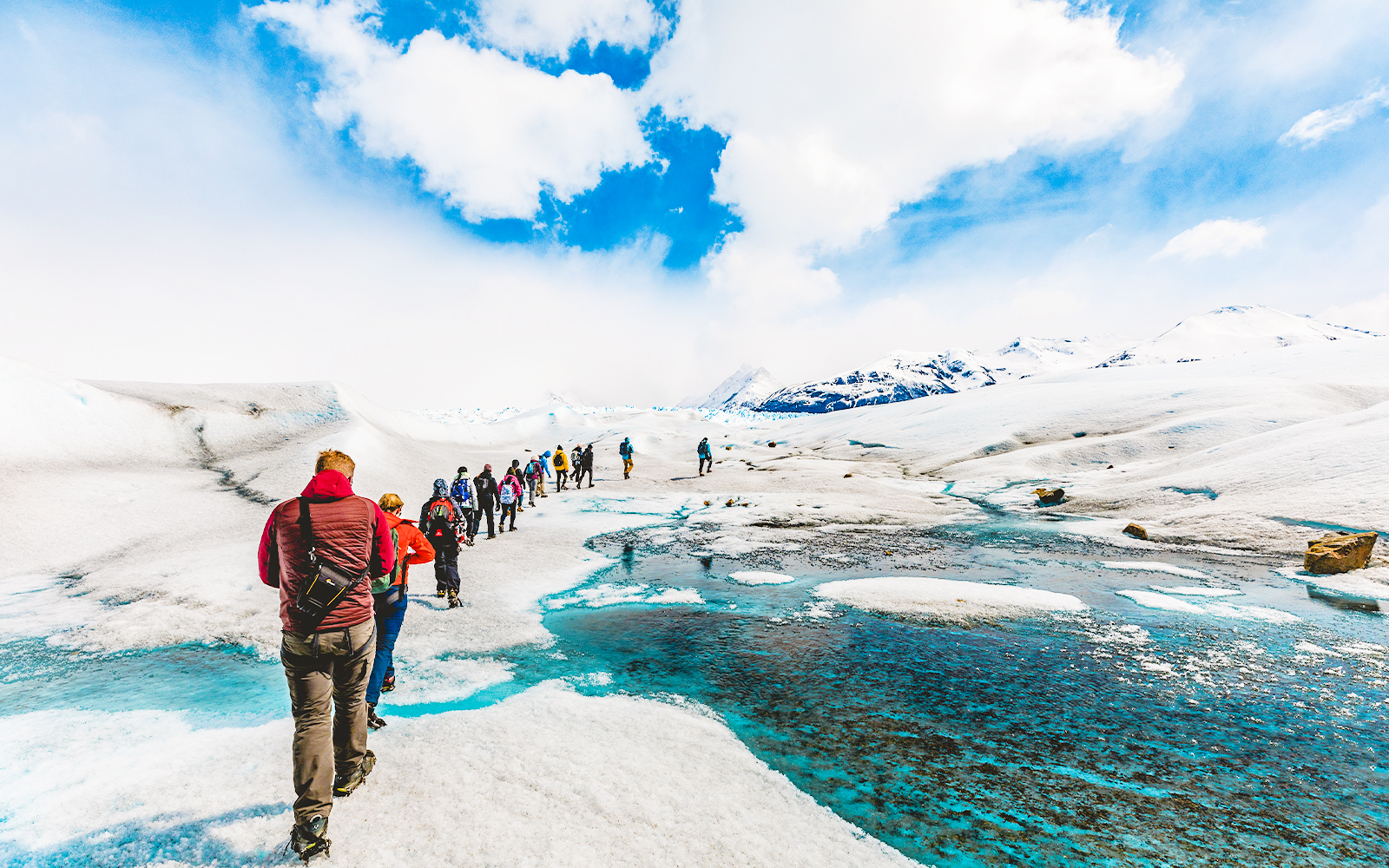 Tourists hiking with a guide on the icy terrain of Perito Moreno Glacier, Argentina.