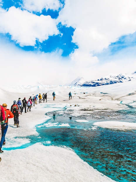 Tourists hiking with a guide on the icy terrain of Perito Moreno Glacier, Argentina.