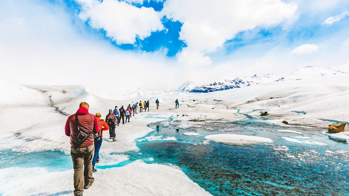 Tourists hiking with a guide on the icy terrain of Perito Moreno Glacier, Argentina.