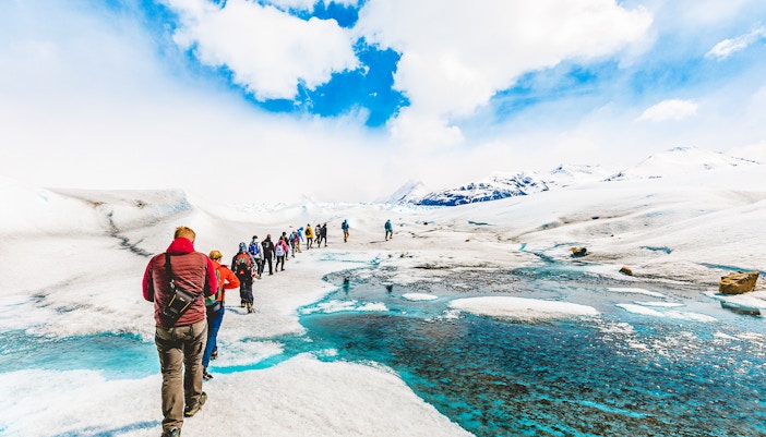 Tourists hiking with a guide on the icy terrain of Perito Moreno Glacier, Argentina.