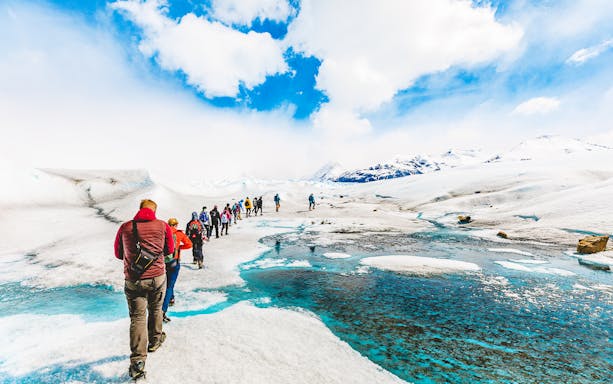 Tourists hiking with a guide on the icy terrain of Perito Moreno Glacier, Argentina.
